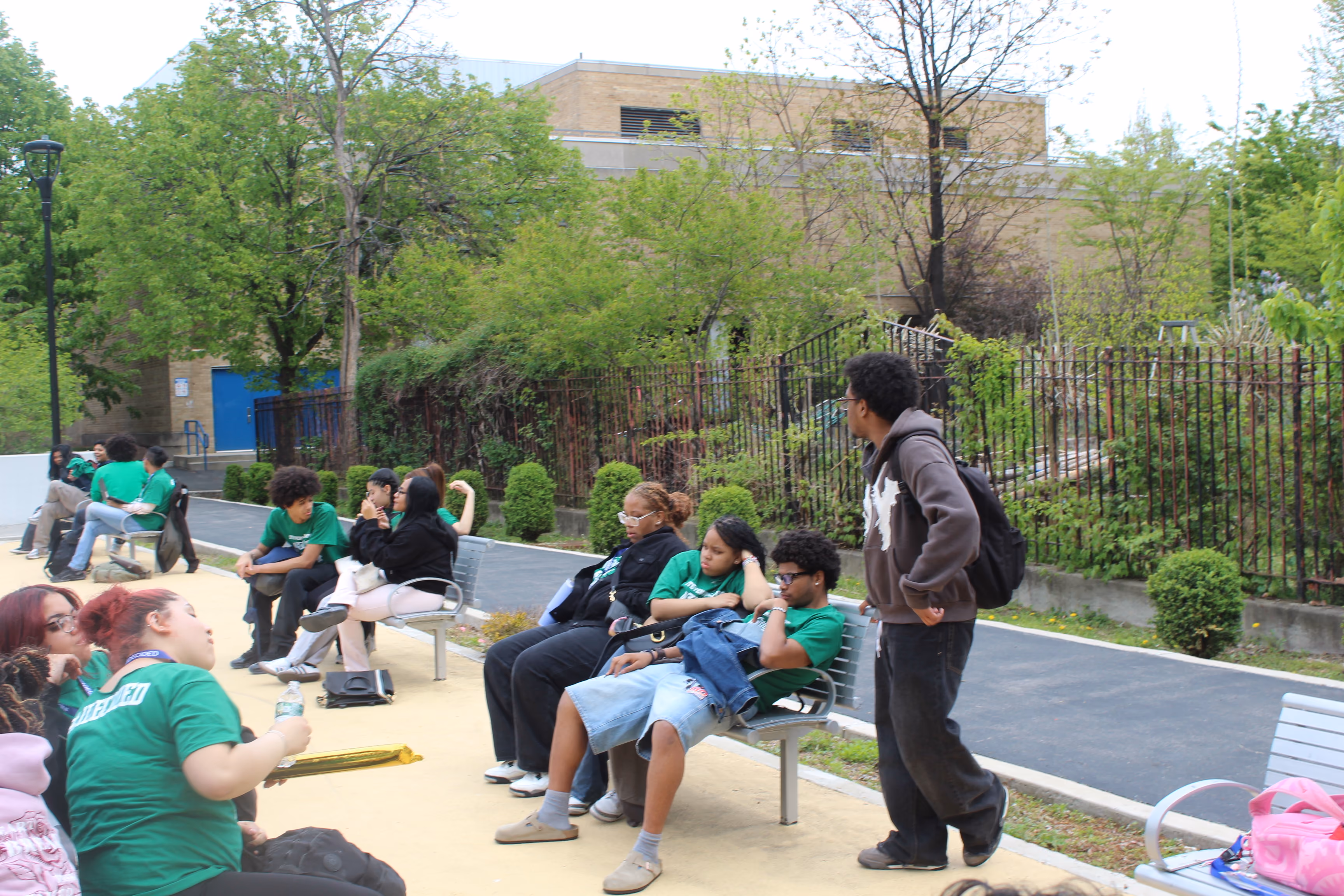 Students gathered outdoors on benches near school building
