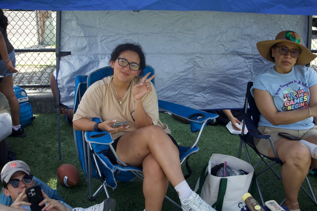 Students and staff relaxing under a tent at Bronx Compass Field Day
