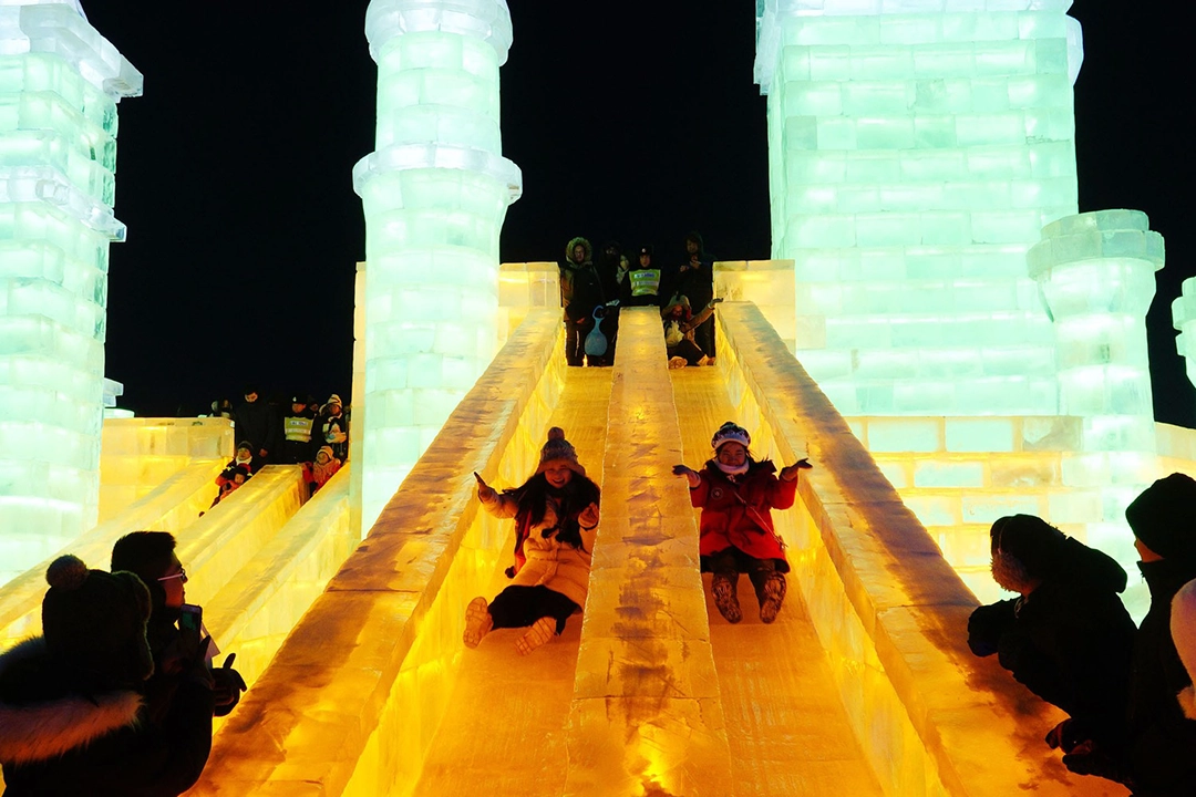 Tourists slide down illuminated ice slides on opening day, January 5, 2019. The Atlantic.