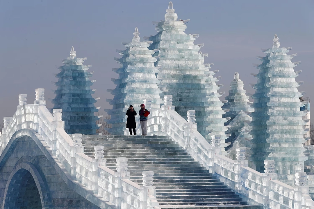 Visitors walk around ice sculptures during the annual ice festival in Harbin on January 7, 2019. The Atlantic.