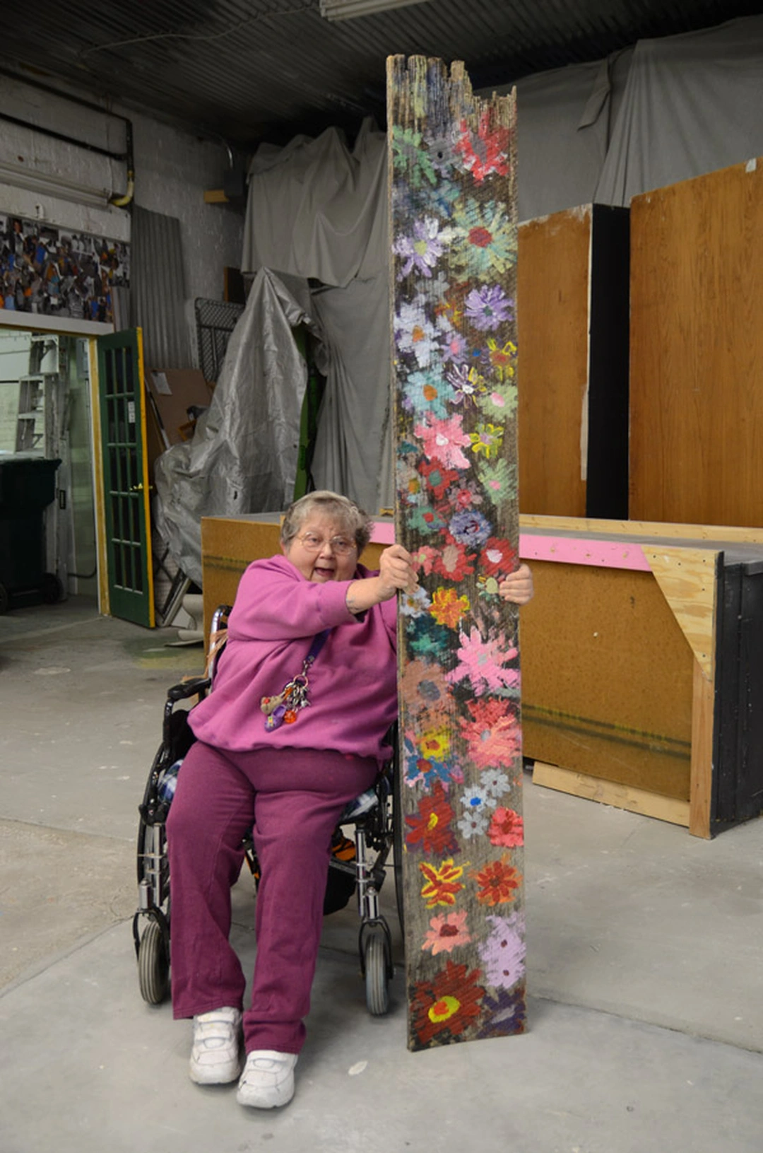 Audrey, an artist at Visionaries and Voices, with her painted wooden floral artwork in the studio, Cincinnati.