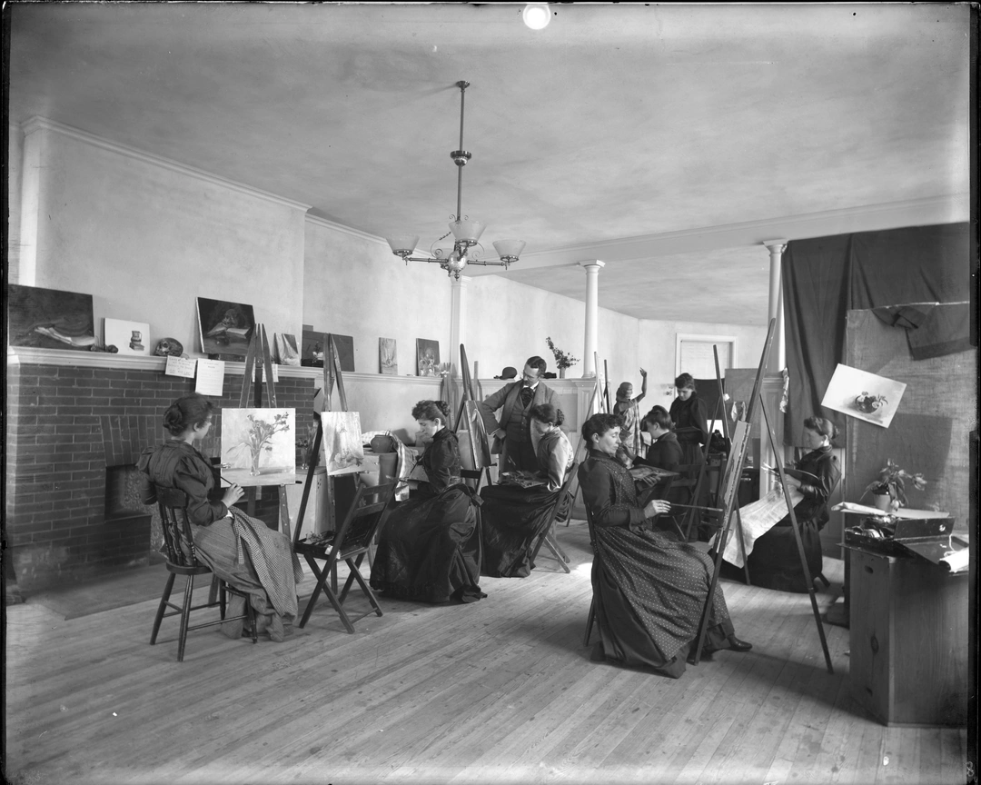 Artists working from easels in an uninstructed figure drawing study session with a live model.