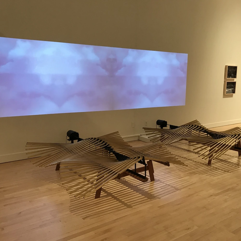 John Douglas Powers kinetic sculpture Haliades showing undulating wooden slats, motor drive, and sky projection.