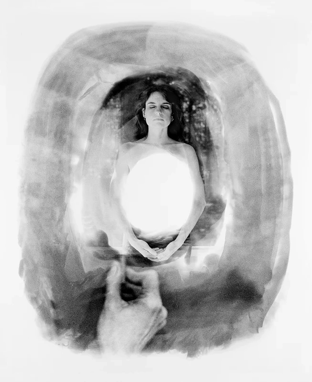 A black-and-white photographic montage shows a woman holding a bright oval of light before her torso, surrounded by overlapping portraits.