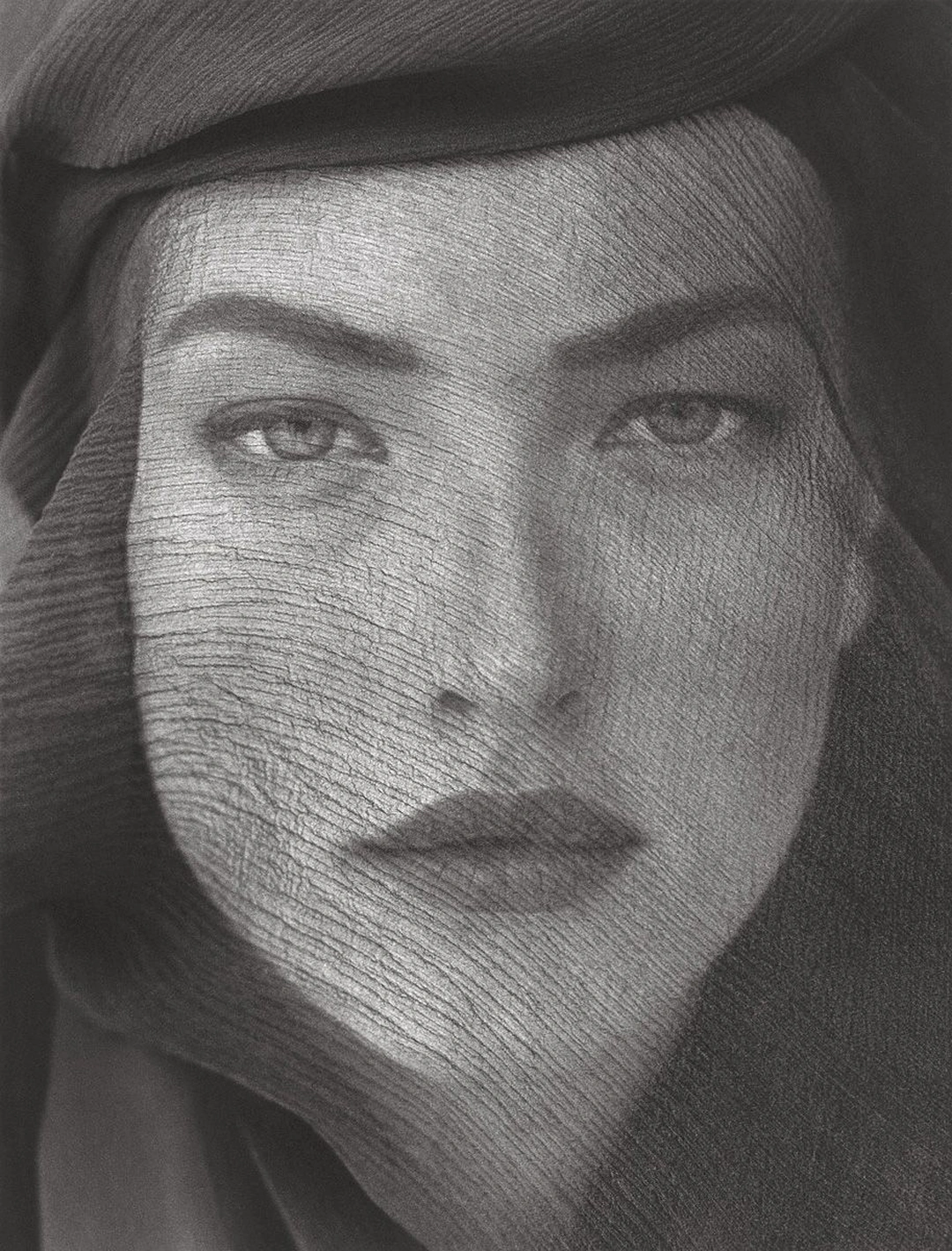 Close-up portrait of a woman whose face is covered by a sheer dark veil. Herb Ritts “Tatjana, Veiled Head, Joshua Tree” 1988 Platinum print Image: 48.3 x 36.8 cm (19 x 14 1/2 in.) Sheet: 60 x 47.5 cm (23 5/8 x 18 11/16 in.) Mat: 76 x 63.5 cm (29 15/16 x 25 in.) Joshua Tree, California, United States, North America The J. Paul Getty Museum, Los Angeles © Herb Ritts Foundation