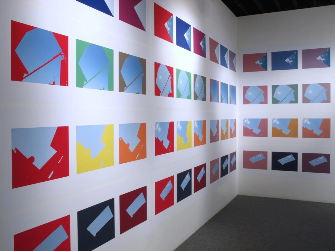 Oblique view along a gallery wall covered with red, green, yellow and blue sky photographs, continuing onto the far wall. Stephen Berens, “Thinking of Pinturicchio (While Looking Out Sol LeWitt’s Windows),” 2010-2012, archival inkjet prints on paper mounted directly on the wall, each panel: 24 x 70 inches. Photo by Chris Gomien.