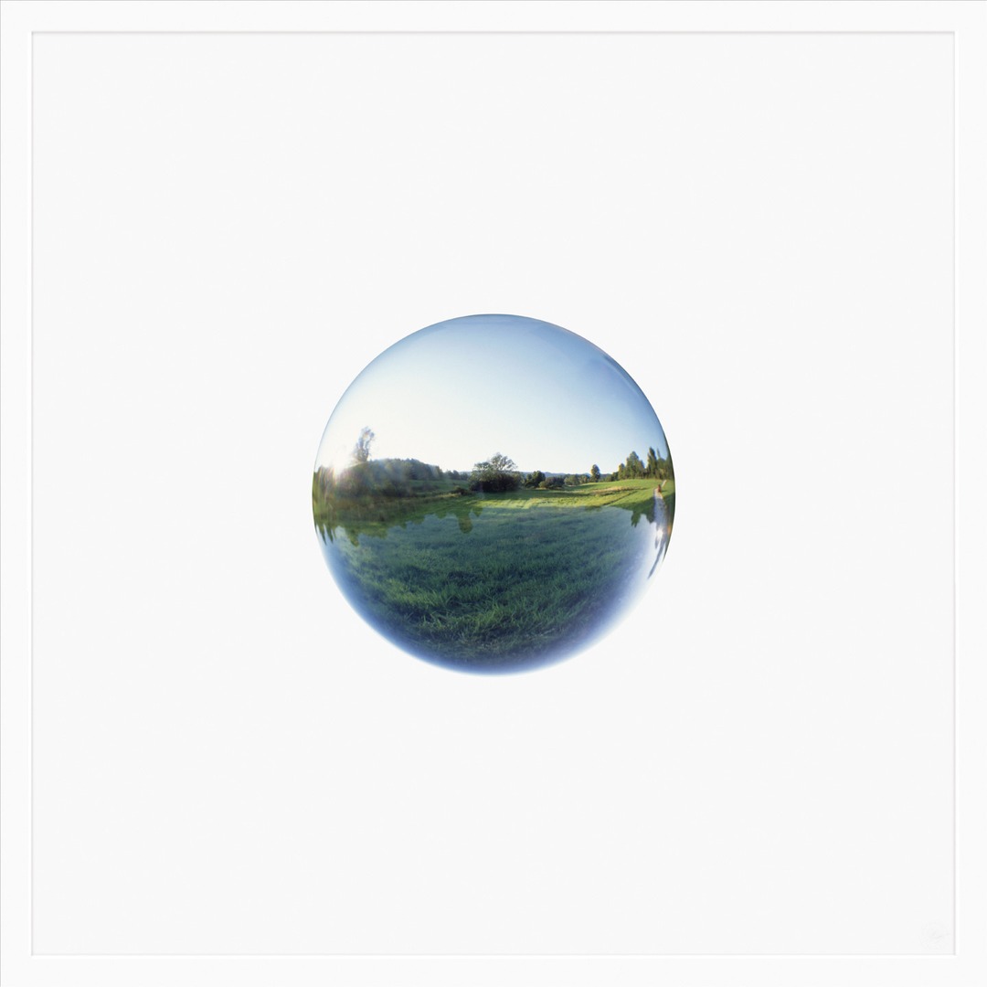 A glass crystal ball reflecting a green landscape, centered on a white background.
