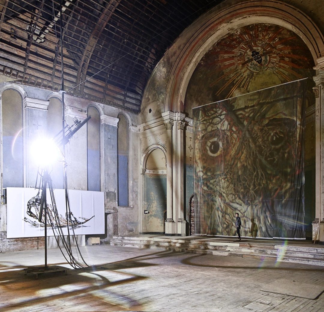 A bright arc lamp stands beside an enormous photographic print of two eyes and branching veins in the church apse. Doug & Mike Starn, Gravity of Light, installation view at Holy Cross Church, Cincinnati, 2012.