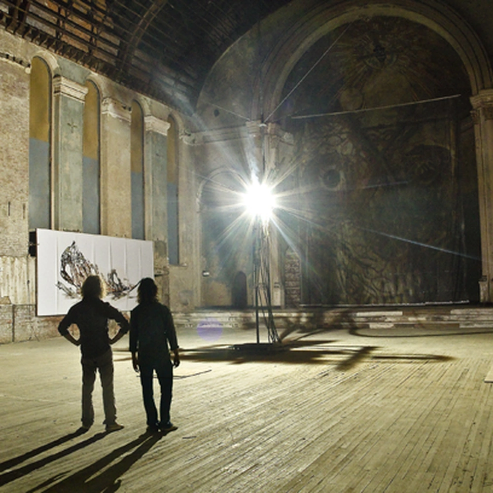 Silhouetted visitors and a carbon arc lamp inside Holy Cross Church.