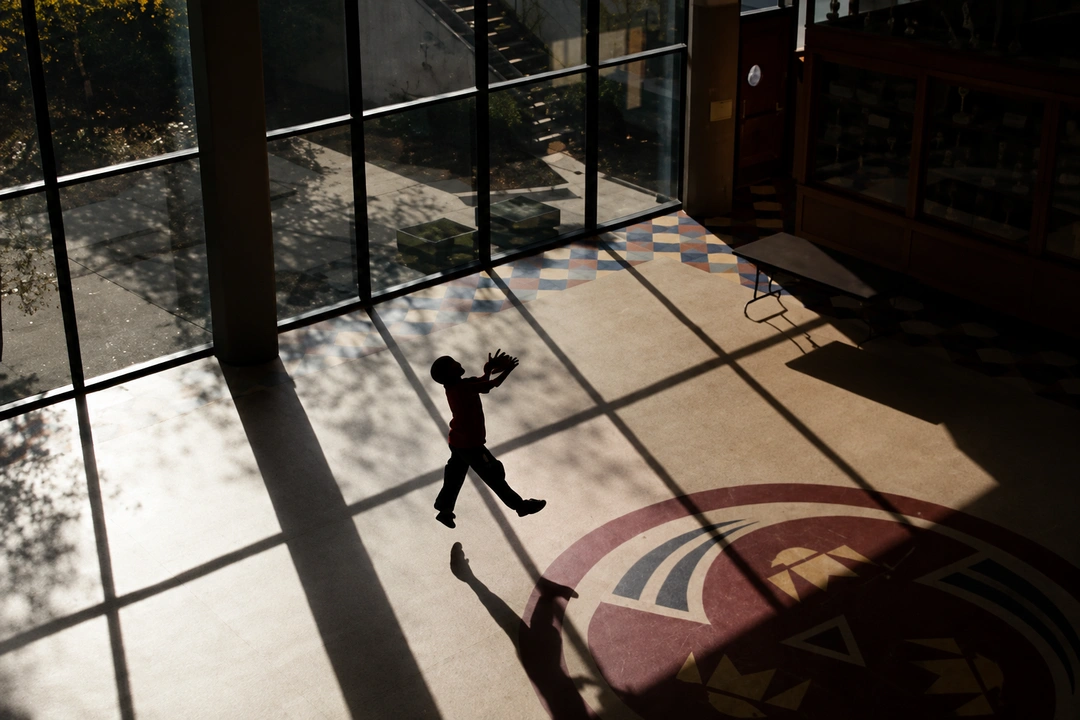 Child in silhouette backlit inside the Indian Center, long shadows on the floor.
