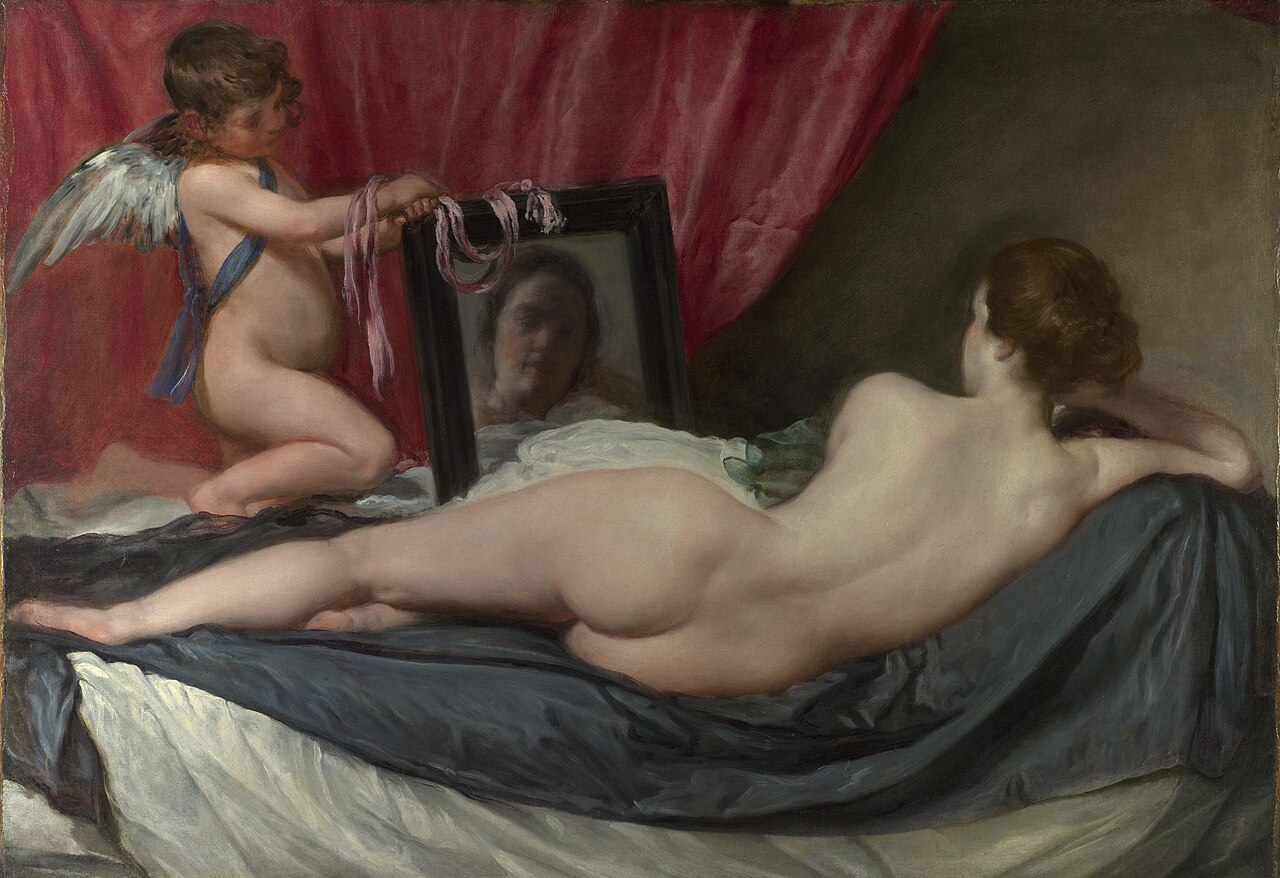 Diego Velázquez’s Rokeby Venus: a nude Venus reclines on a bed, seen from behind, while a winged cupid holds up a mirror reflecting her face; a deep red curtain behind them.