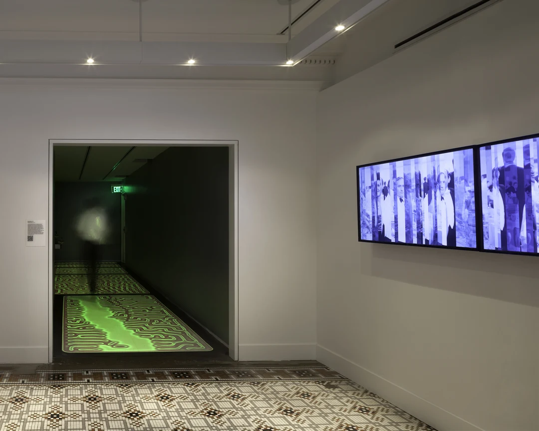 Brian Knep's Healing Tiles at 21C Museum Hotel, Cincinnati: glowing green maze-patterned floor tiles in a dark hallway, with a blurred figure walking.