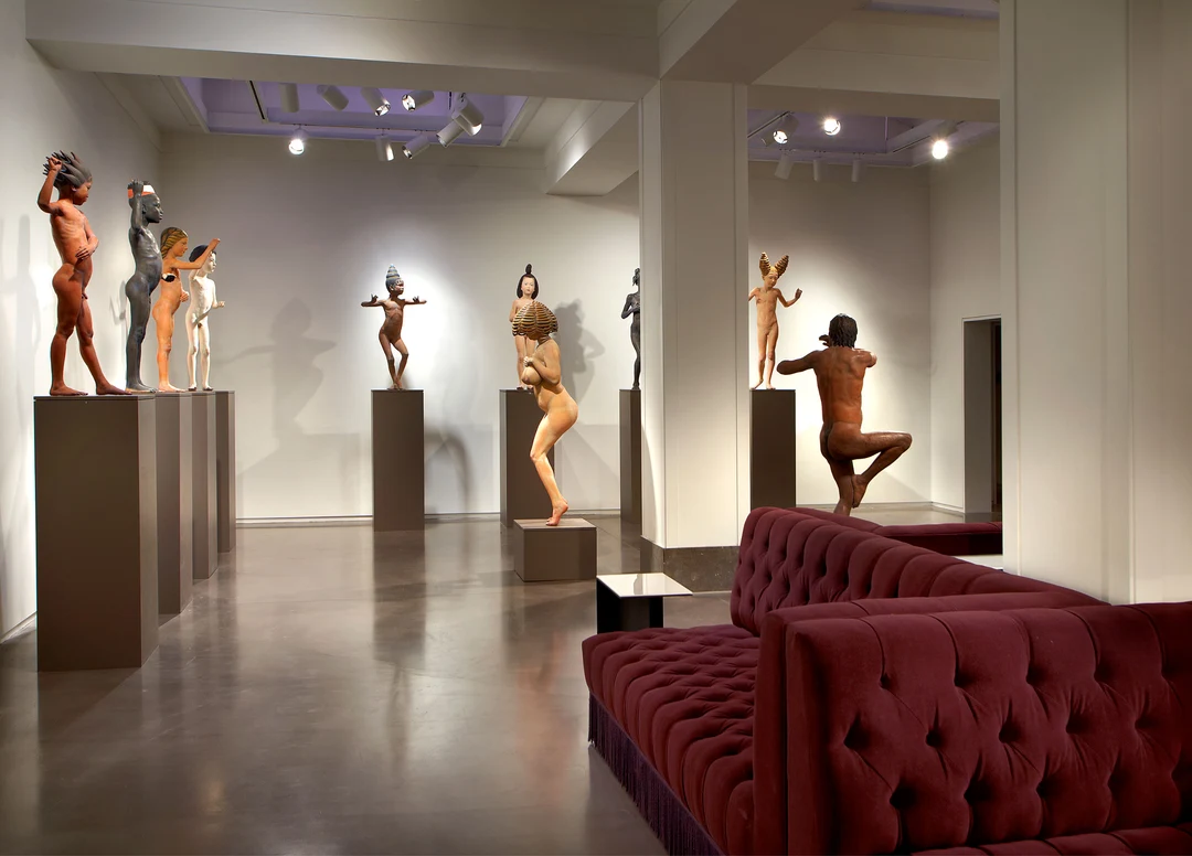Gallery at the 21C Museum Hotel, Cincinnati: figurative sculptures on pedestals in a white gallery room with a red velvet sofa.