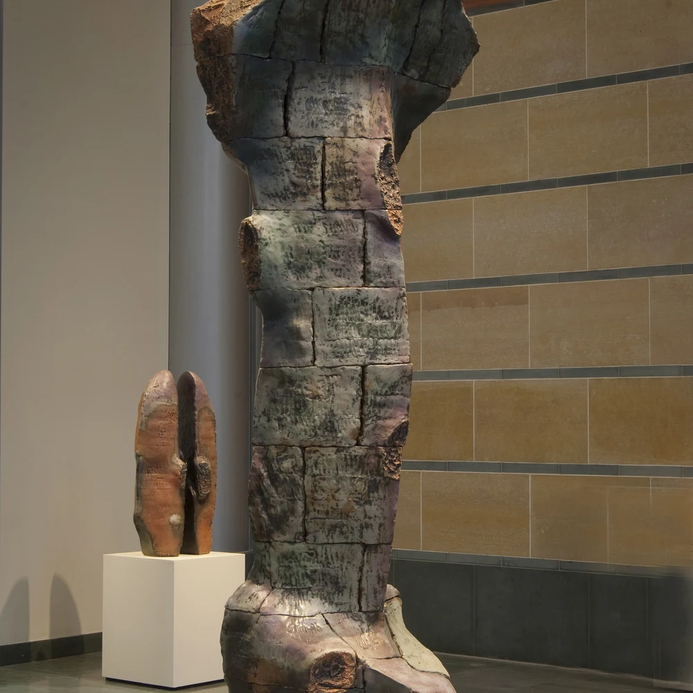 Serpent by Robert Pulley: a tall, craggy ceramic sculpture of stacked, rock-like forms in earthy brown and grey tones, standing in a gallery.