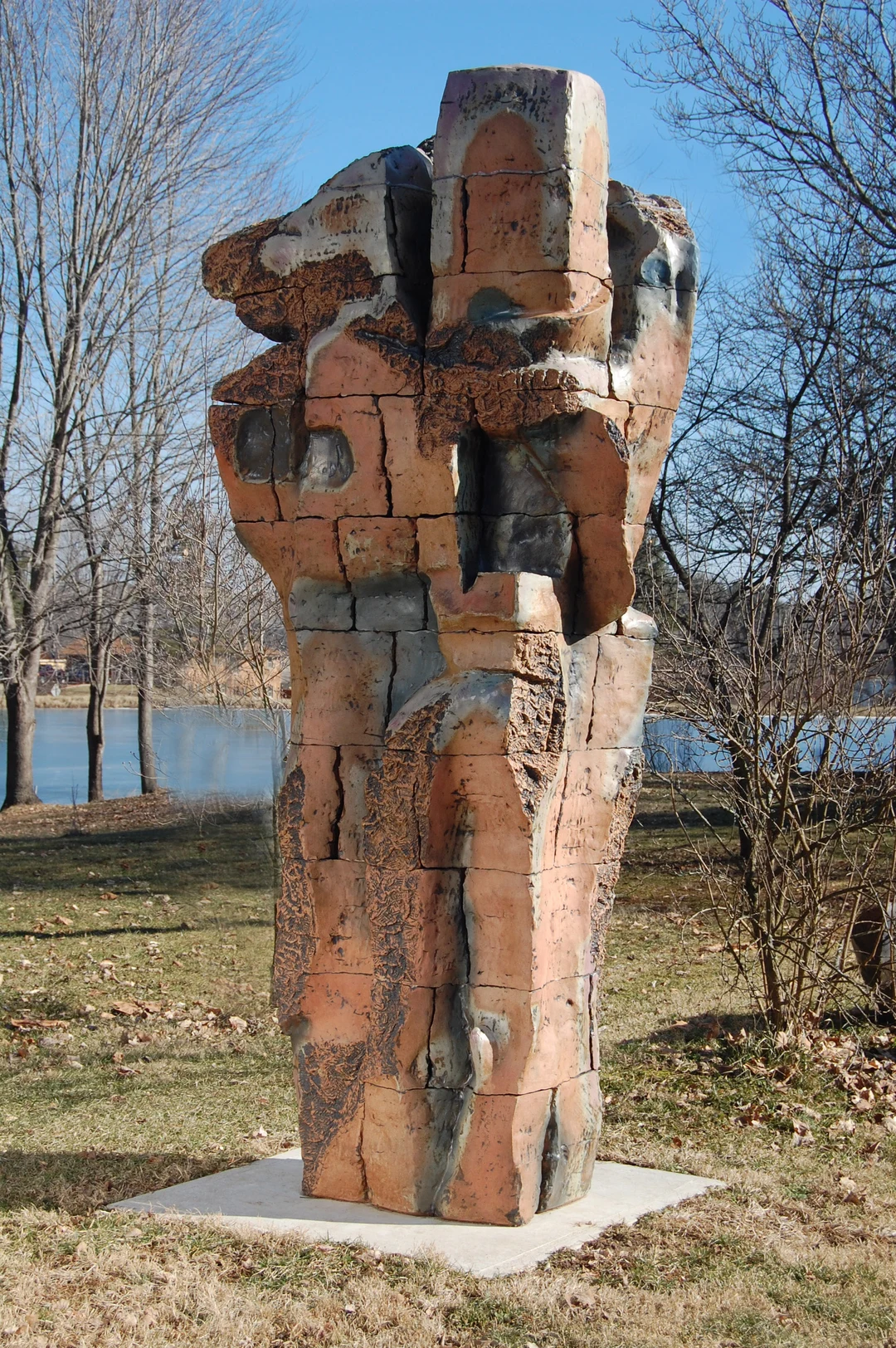 Daughter of the Moon by Robert Pulley: a tall, reddish ceramic totem-like sculpture with rough, organic surfaces, installed outdoors.