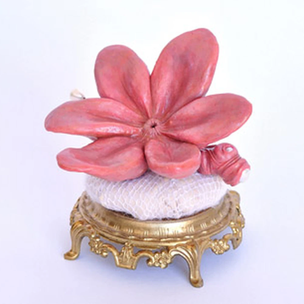 A pink flower sculpture on an ornate gold base, exhibited in the Botanical show.