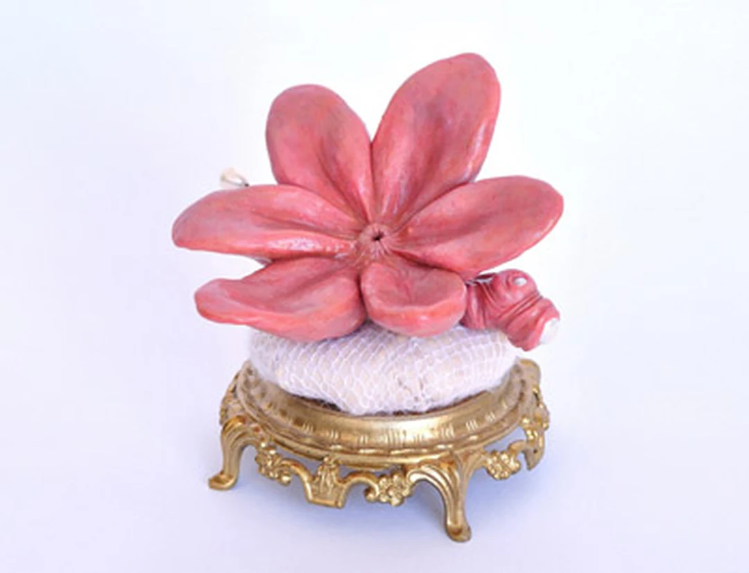 A pink flower sculpture on an ornate gold base, exhibited in the Botanical show.