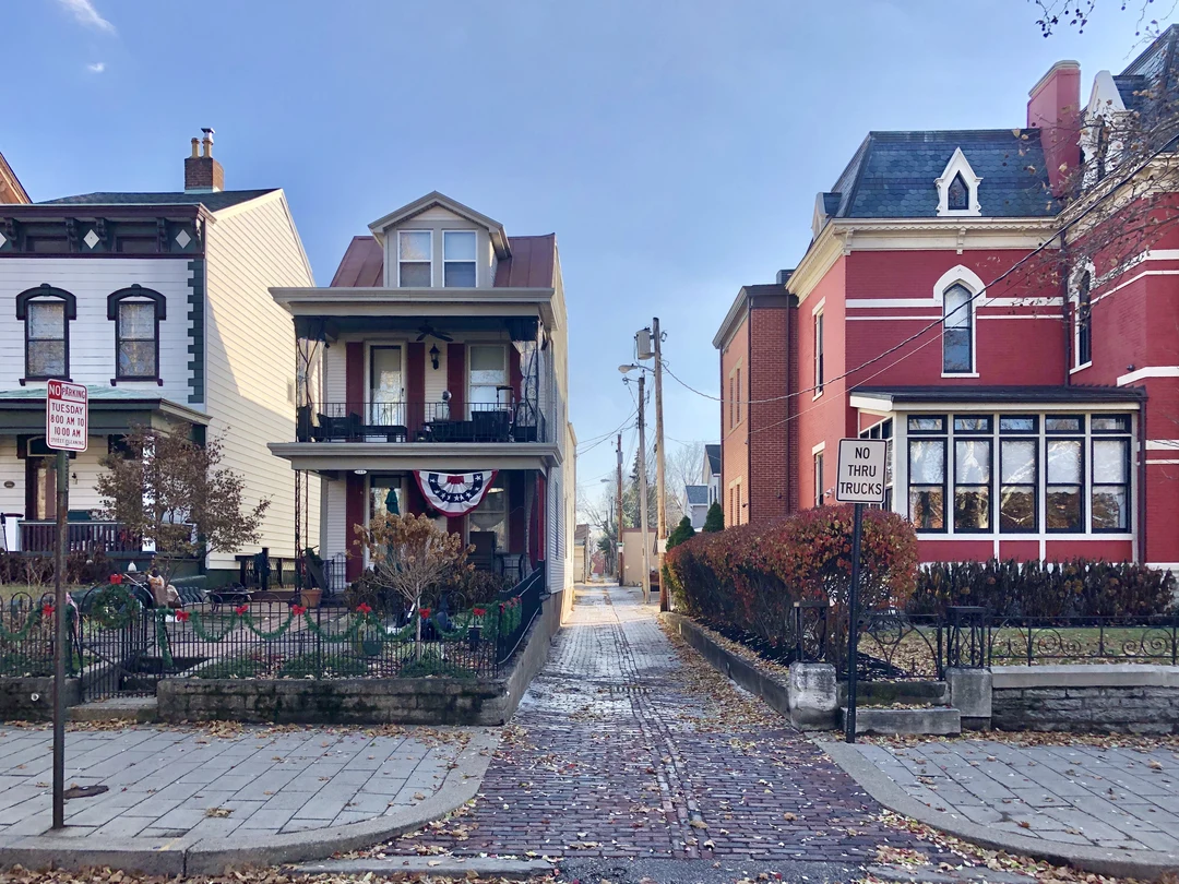 Brick alley between historic houses on 6th Street in Mainstrasse Village, Covington, Kentucky, in autumn.