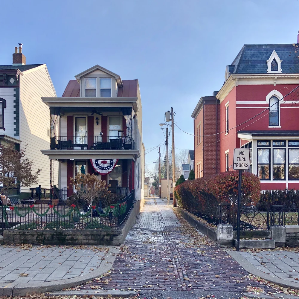 Brick alley between historic houses on 6th Street in Mainstrasse Village, Covington, Kentucky, in autumn.
