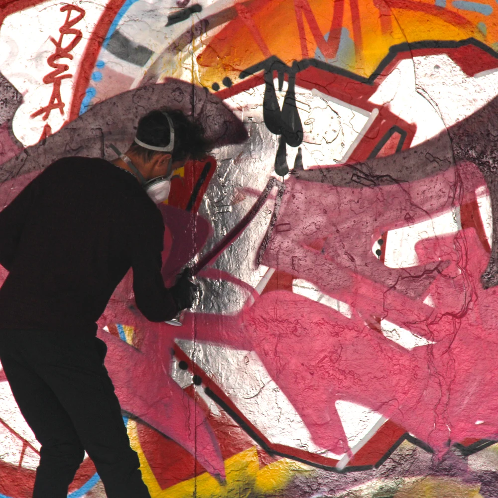 A skateboarder jumping in mid-air at the Southbank skate park in London, with colorful graffiti-covered walls behind.