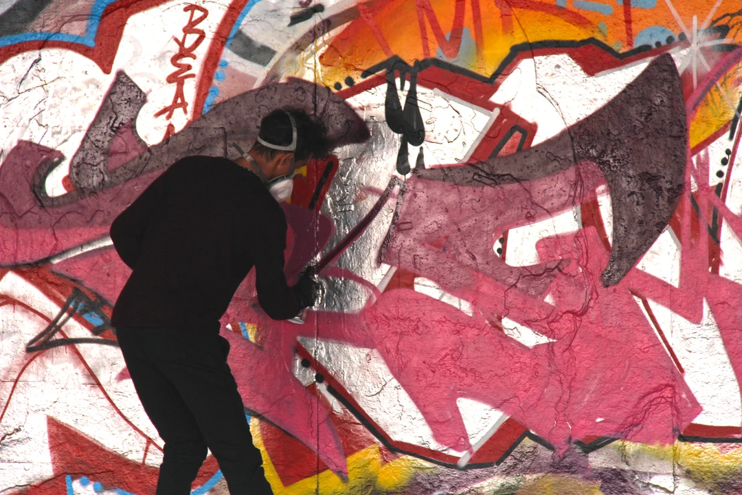 A skateboarder jumping in mid-air at the Southbank skate park in London, with colorful graffiti-covered walls behind.
