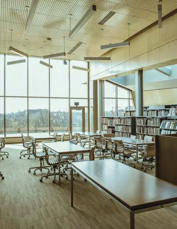 Bright modern library reading room with long wooden tables and rolling chairs, floor-to-ceiling windows overlooking the city, and bookshelves along the right wall. The new Mary R. Schiff Library and Archives in the Longworth Wing of the Cincinnati Art Museum. Image from Cincinnati Art Museum. (Related image located during this archive's reconstruction.)