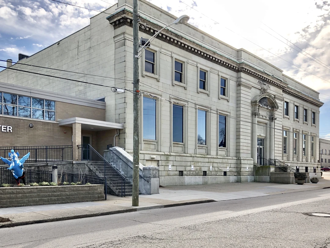 The Carnegie in Covington, Kentucky: a Beaux-Arts limestone building with tall arched windows and a corner entrance, seen from the street under a cloudy sky.