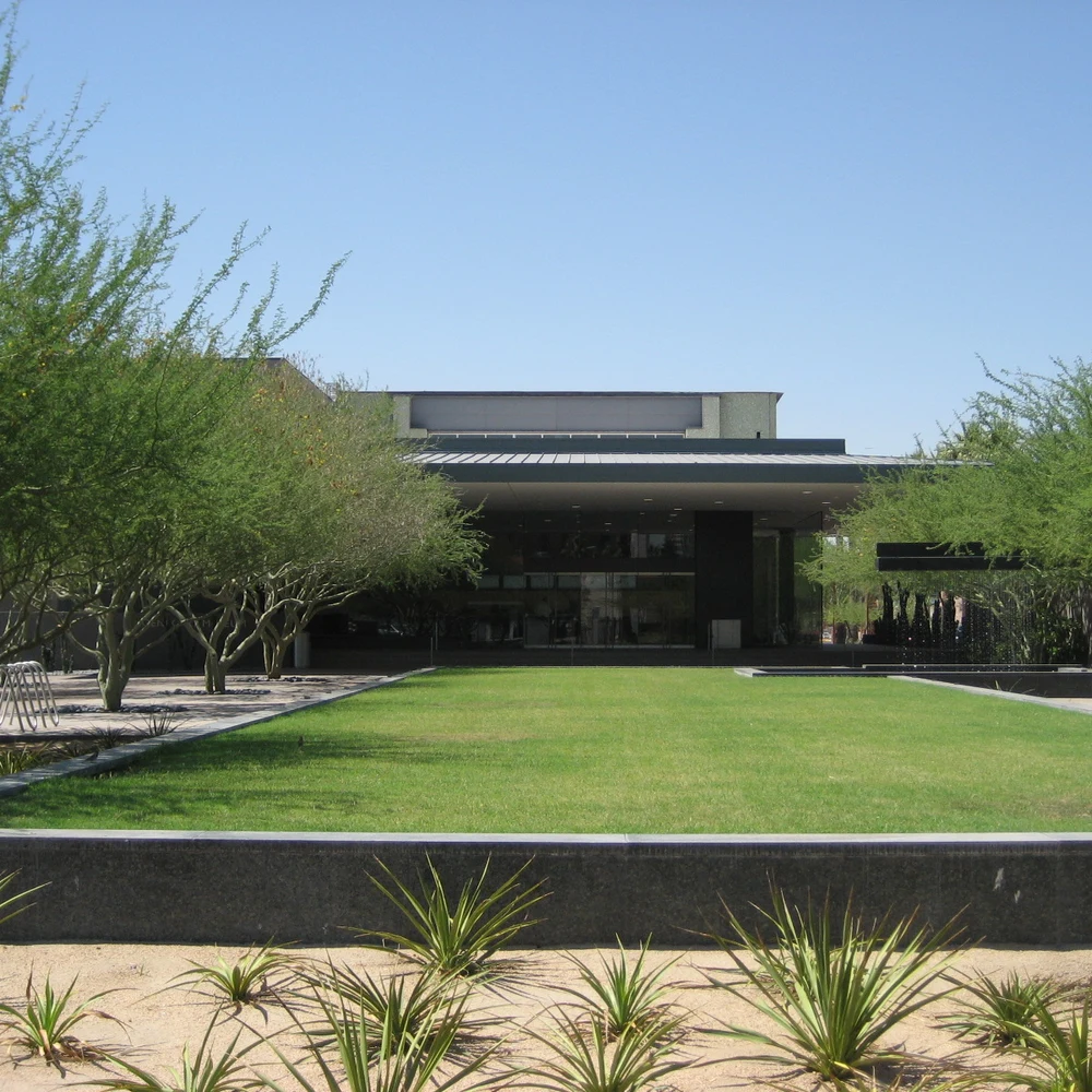 Main entrance of the Phoenix Art Museum: modern building facade with glass doors, green lawn and desert landscaping.