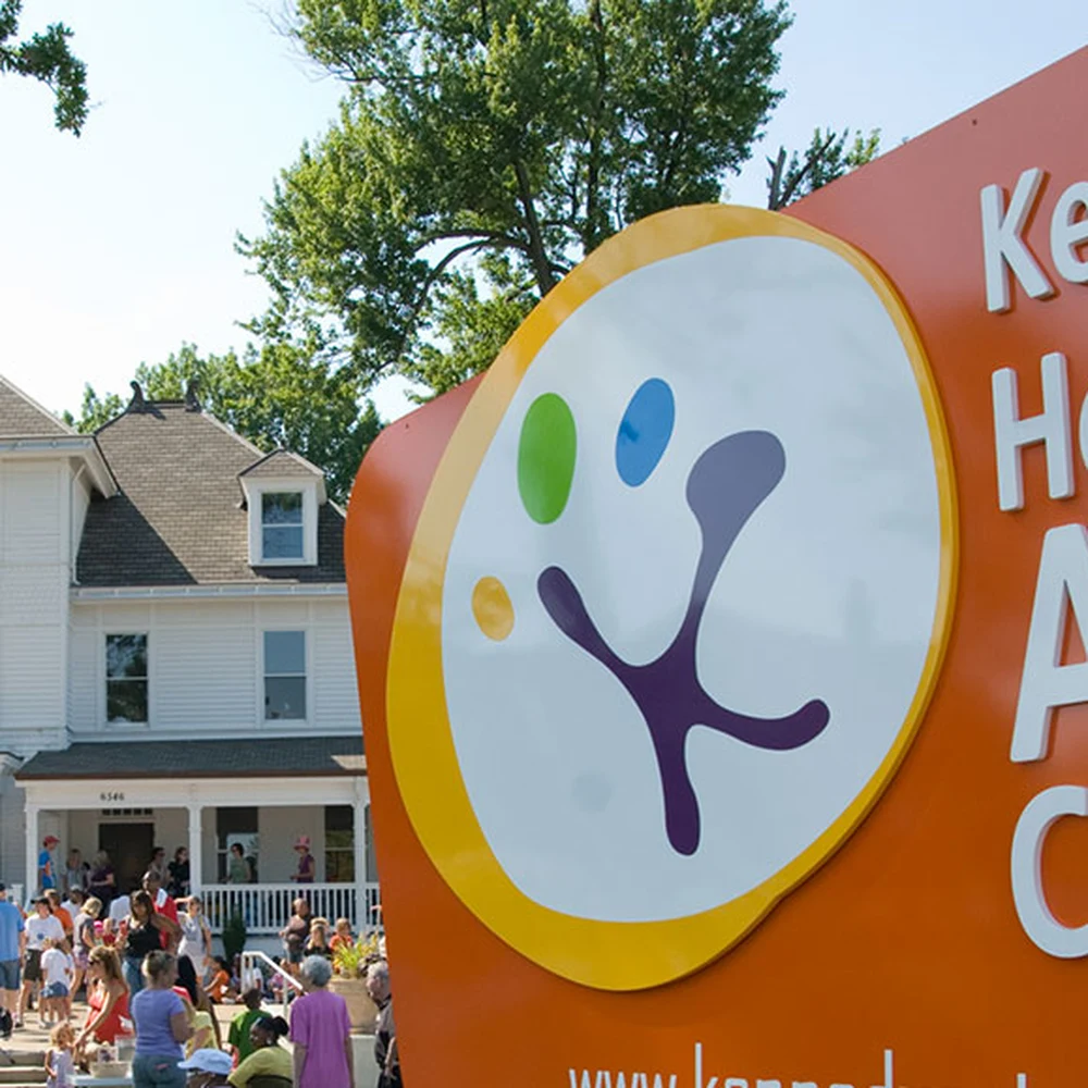 The Kennedy Heights Arts Center sign and historic mansion building during a community event.