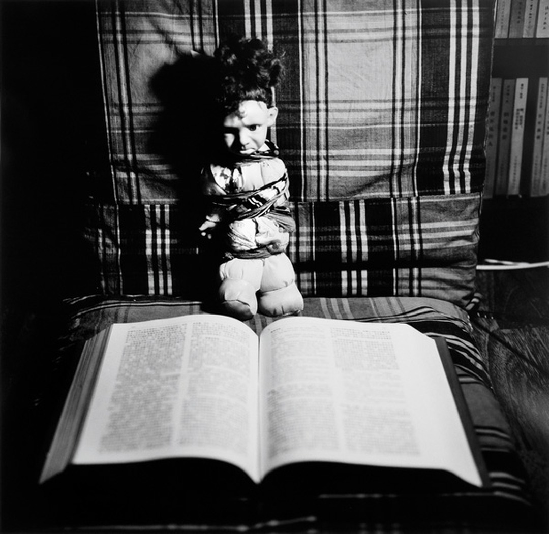 Liu Xia, 'Untitled,' 1996-99: a doll sits on a plaid chair above an open book, black-and-white photograph