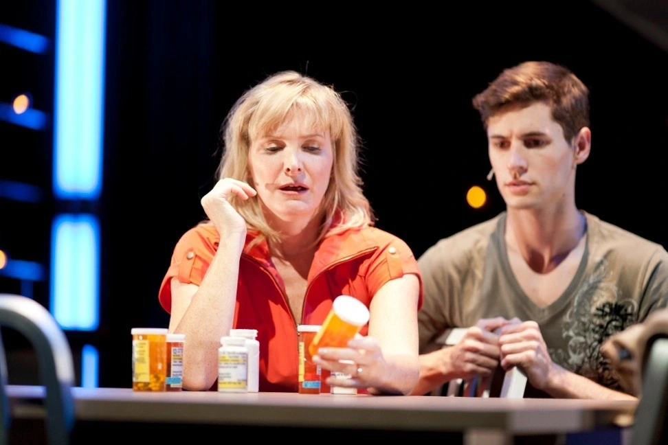 Two actors at a table covered with pill bottles in Ensemble Theatre Cincinnati's production of Next to Normal.