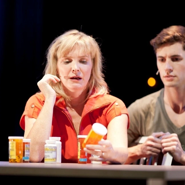 Two actors at a table covered with pill bottles in Ensemble Theatre Cincinnati's production of Next to Normal.