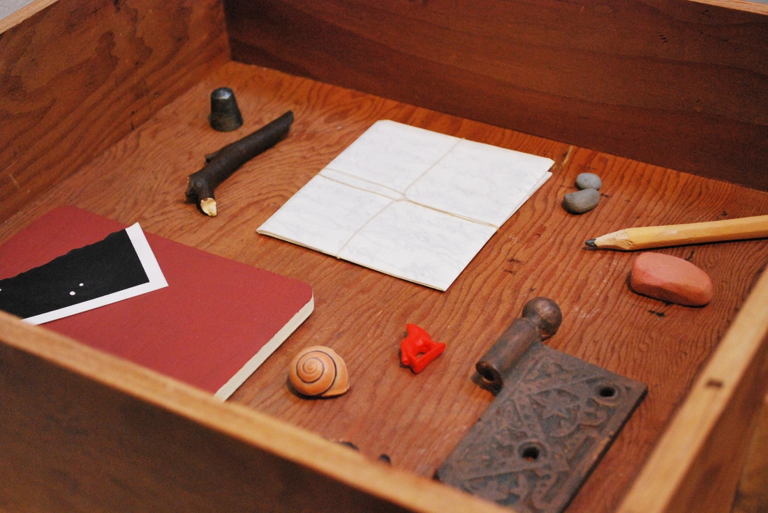 Detail of a wooden drawer containing a red notebook, paper, pencils and sculptural objects. Cynthia Gregory, The Poet's Table, 2012; installation view associated with Of Reference, Of Departure, Of Origin, 2015. Image from the artist's archived website. (Related image located during this archive's reconstruction.)