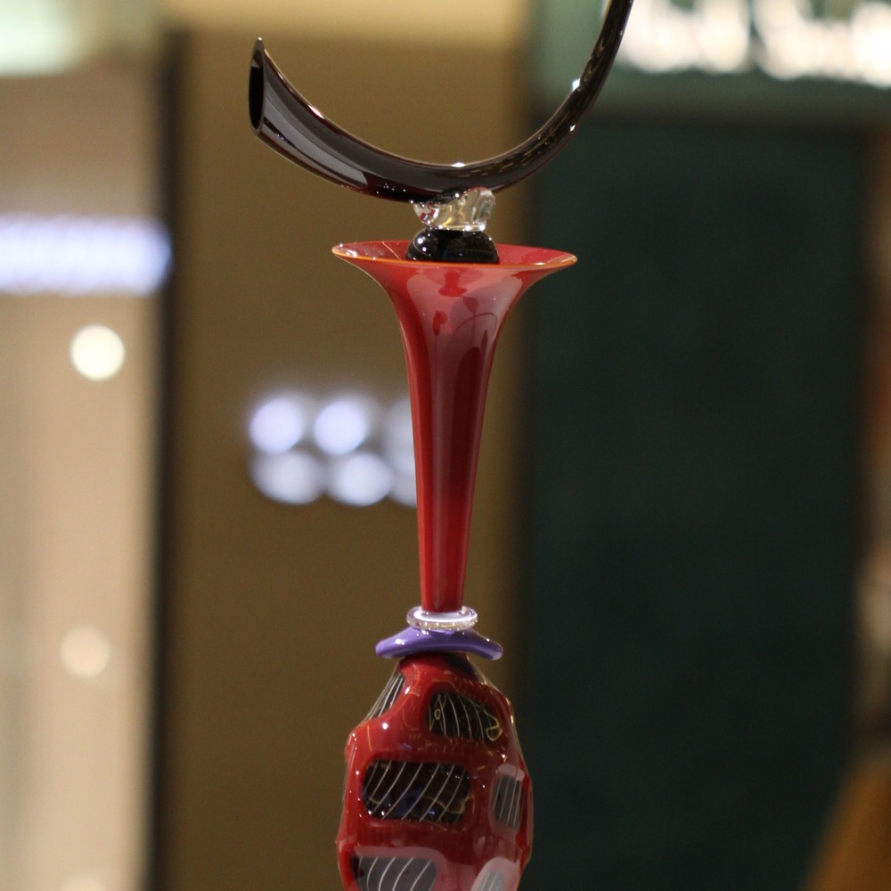 Red art glass vessels, one of them a tall red vessel, photographed at a glass art exhibition