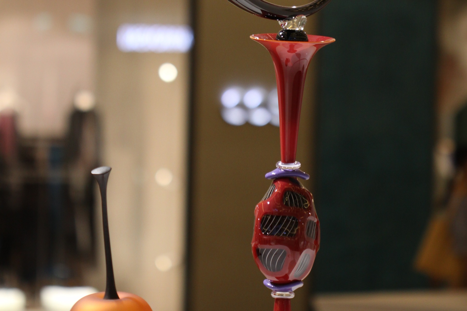 Red art glass vessels, one of them a tall red vessel, photographed at a glass art exhibition
