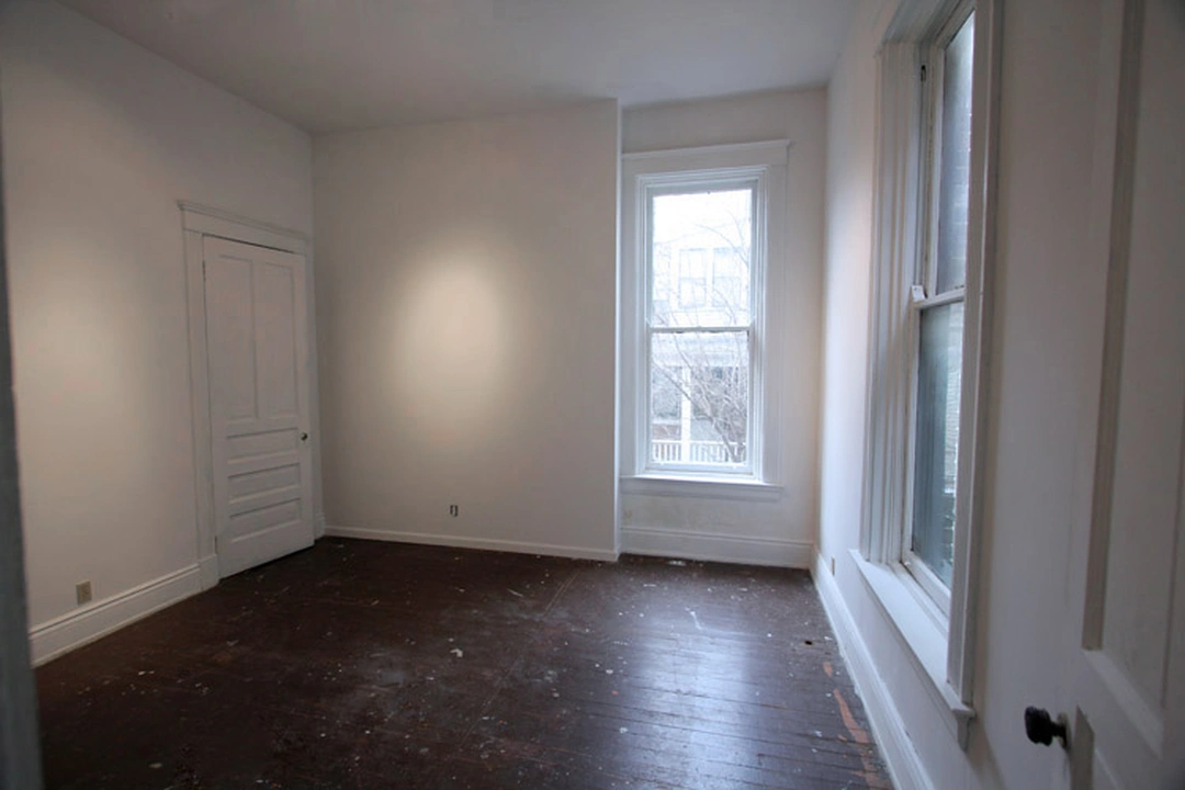 Empty west studio of the Manifest Artist Residency in Cincinnati: white walls, tall windows and a paint-spattered dark wood floor.