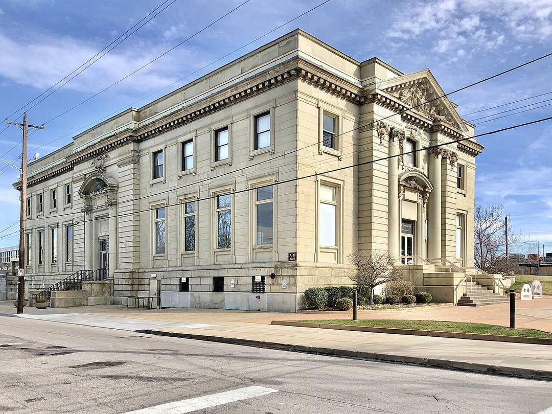 Corner view of The Carnegie in Covington, Kentucky: a Beaux-Arts stone building with rows of tall windows under a blue sky.