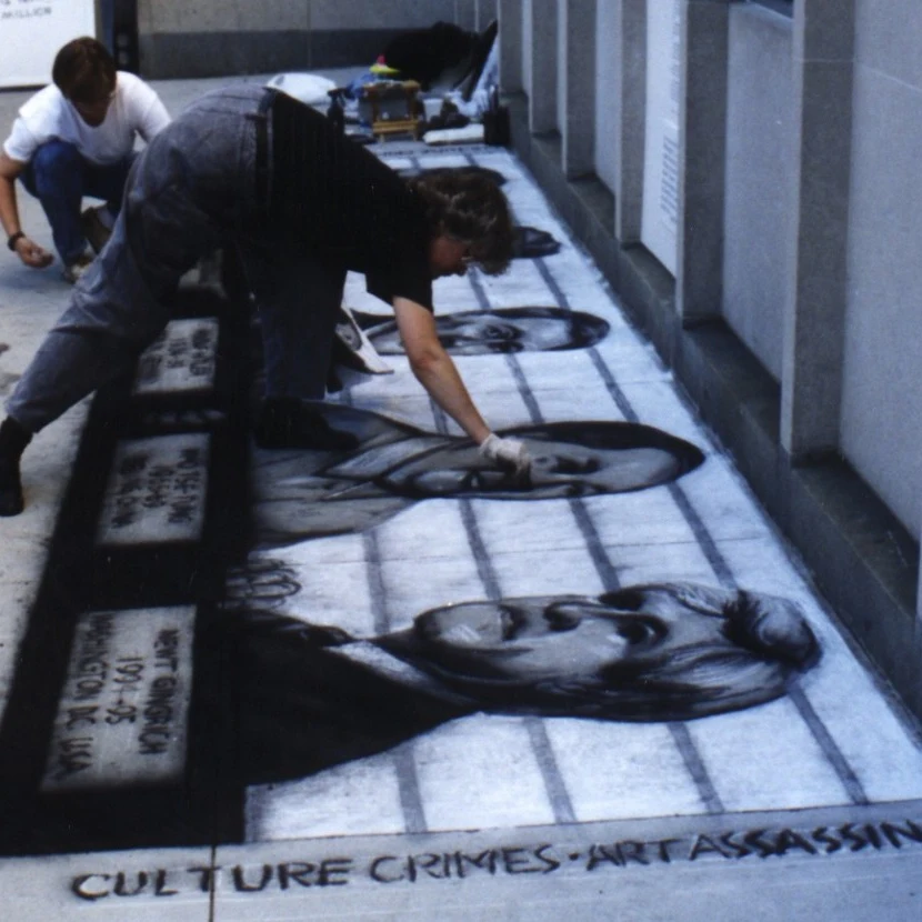 Artist drawing large black-and-white chalk portraits on a sidewalk, with the words 'Culture Crimes, Art Assassins' at the bottom