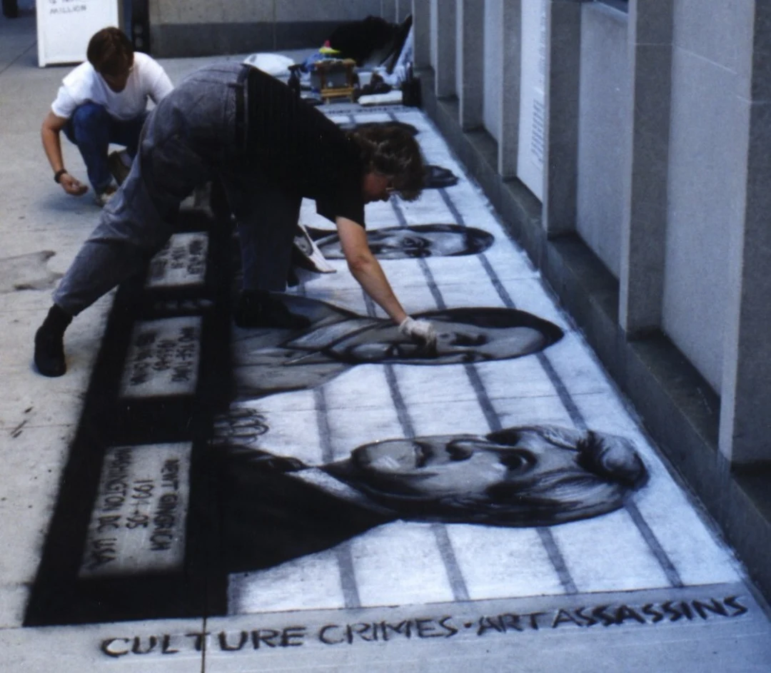 Artist drawing large black-and-white chalk portraits on a sidewalk, with the words 'Culture Crimes, Art Assassins' at the bottom