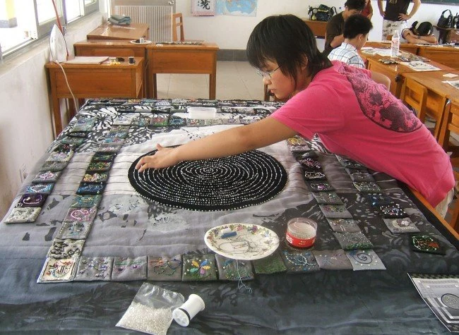 Friendship Tapestry for Liuzhou, China, mixed media tapestry by Jan Brown Checco and Amanda Checco: young woman arranging a circular black-and-white beaded tapestry on a table