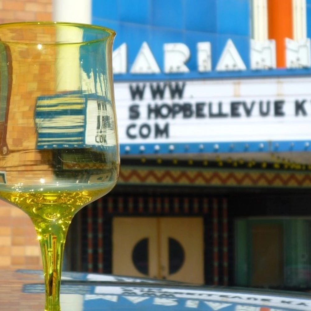 A yellow wine glass in the foreground with the marquee of the Marianne theater in Bellevue, Kentucky, behind it.