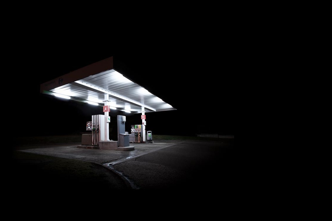 Night photograph of a brightly lit gas station beneath a vast black sky, from Xavier Blondeau's 'Presence Obscure' series.