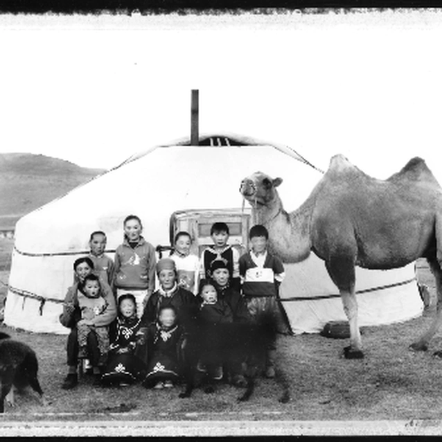 A Mongolian family in traditional dress posed in front of their felt ger.