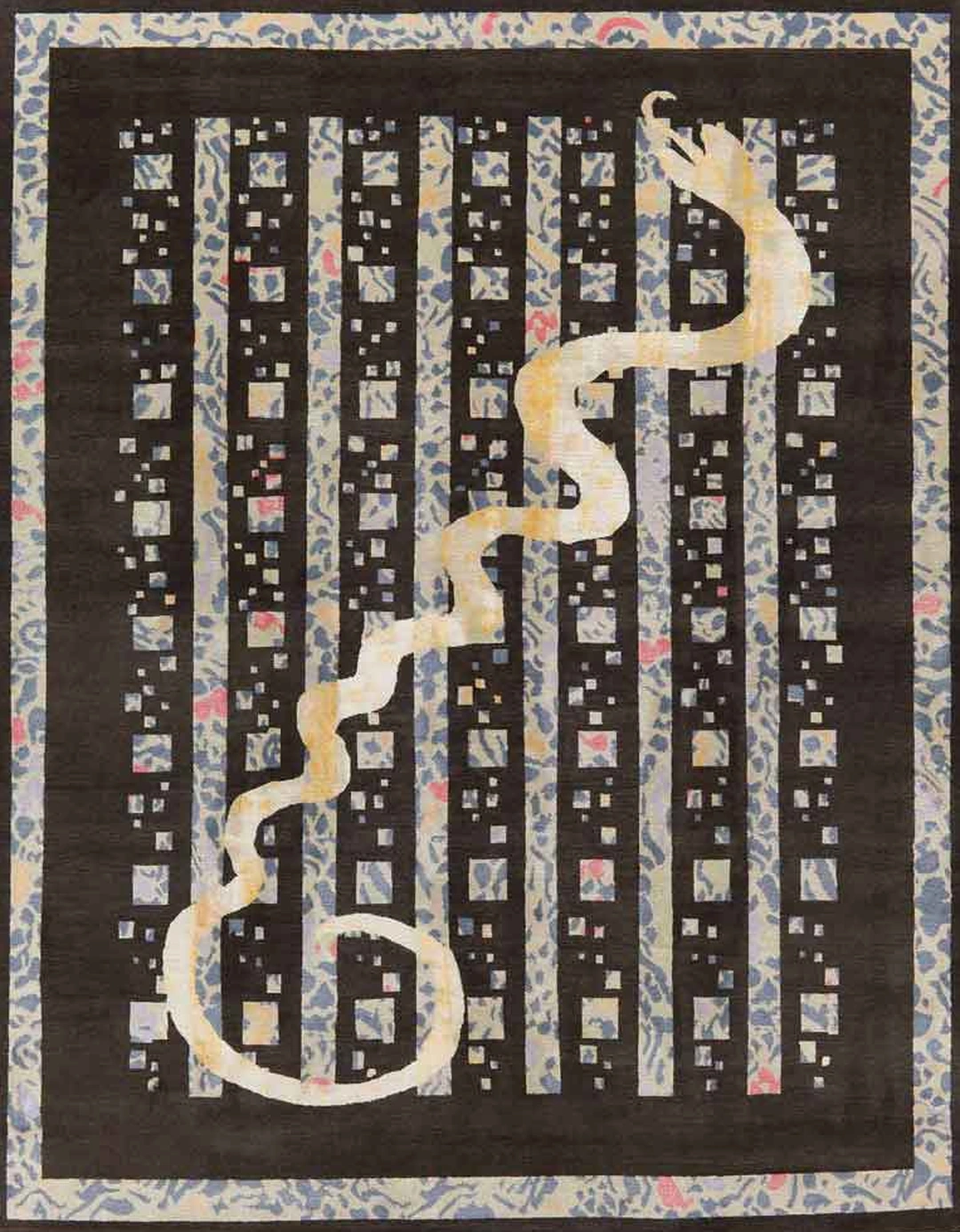 Black rug with an ordered pattern of small squares and bars in muted colors, crossed by a pale sinuous snake from lower left to upper right.