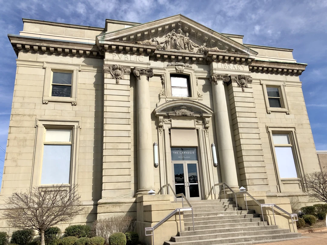 Front entrance of The Carnegie in Covington, Kentucky: a stone Beaux-Arts facade with columns, a carved pediment reading PUBLIC LIBRARY, and a glass door marked THE CARNEGIE.