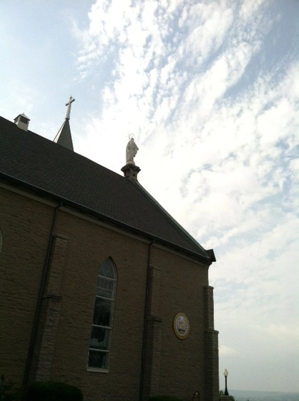 Brick church with a statue on its roofline under a cloudy sky, Mt. Adams, Cincinnati