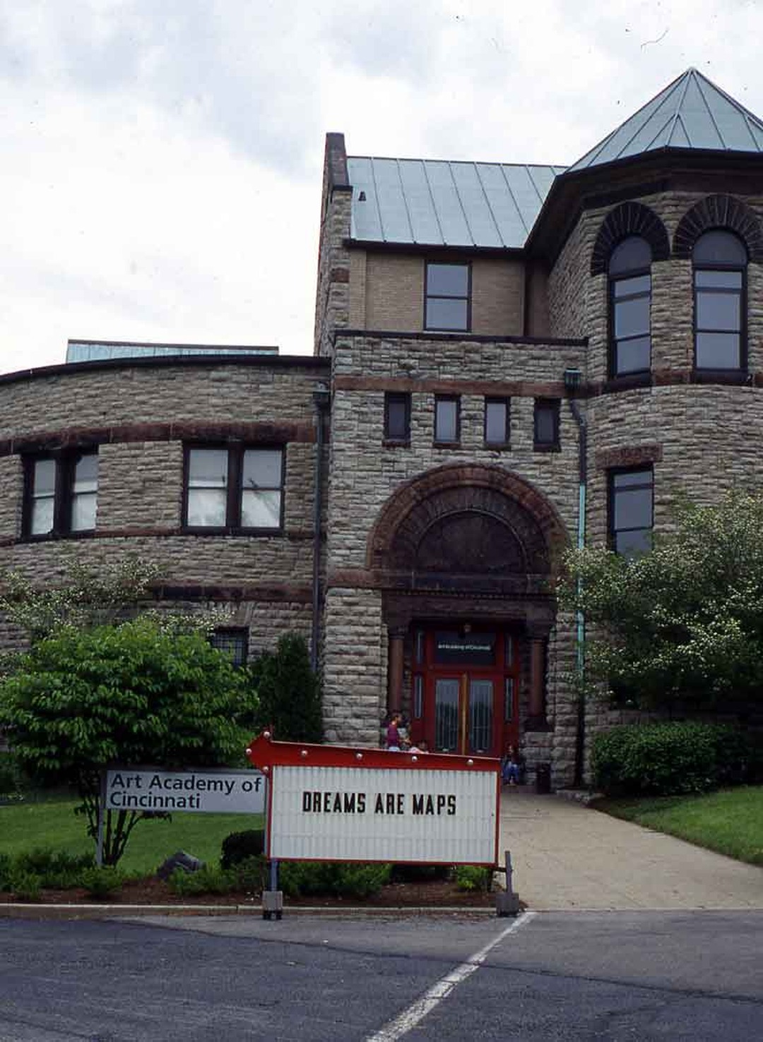 Portable changeable-letter sign reading 'DREAMS ARE MAPS' in front of the Art Academy of Cincinnati building