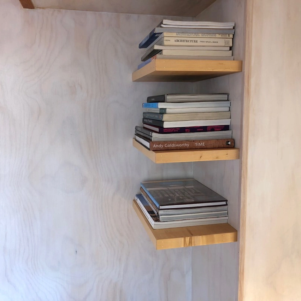Curated art books stacked on wooden shelves.