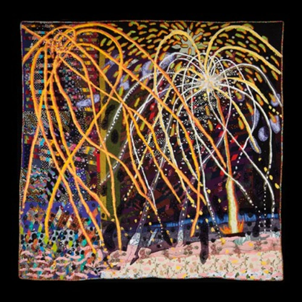 Art quilt with orange and white firework bursts against a dark patterned night sky above a pink embroidered flower garden