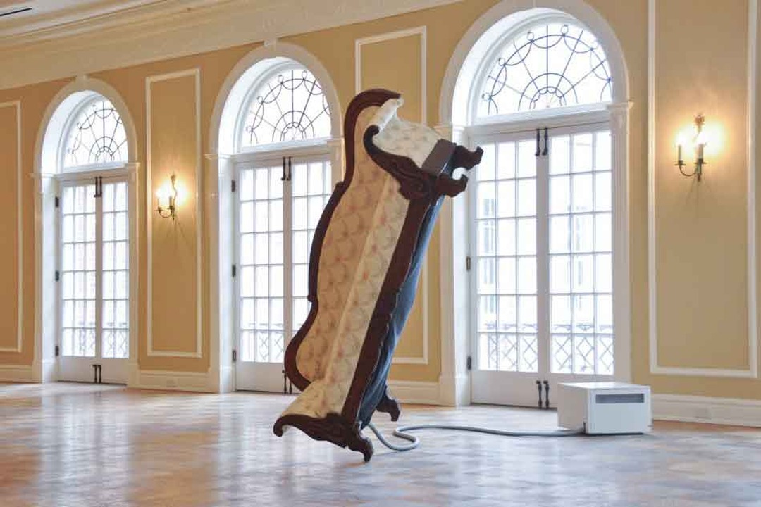 Victorian sofa balanced upright on one end in a ballroom, installation by Tonski